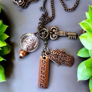 Unique bronze necklace key and charm details clear glass bead and 'breathe' tag.